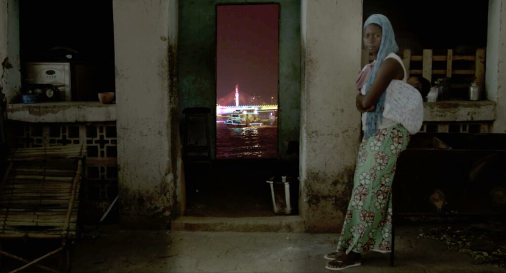 Une femme devant une porte donnant sur un paysage de ville au loin. ©valerie Osouf
