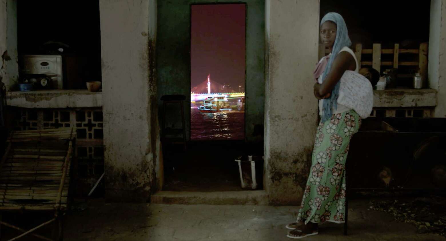 Une femme devant une porte donnant sur un paysage de ville au loin. ©valerie Osouf